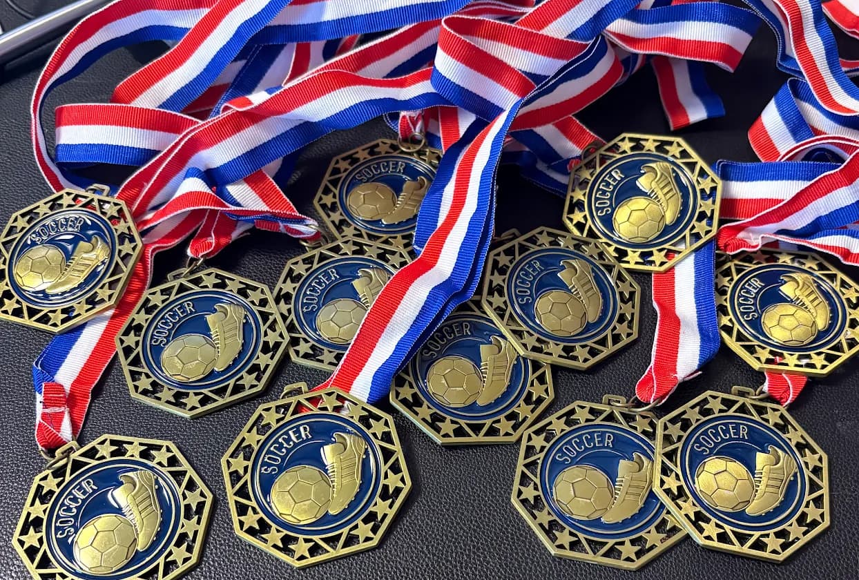 A full youth-team set of custom laser-engraved soccer medals with red-white-blue ribbons by Print Habit